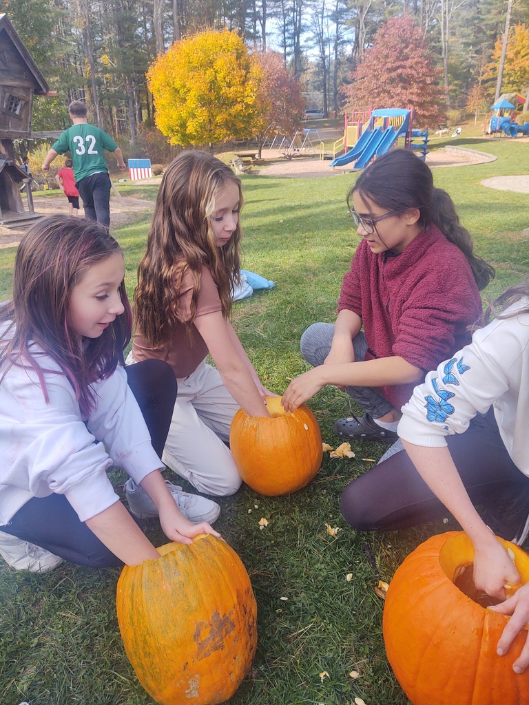 a group of little girls are scooping out the insides of pumpkins