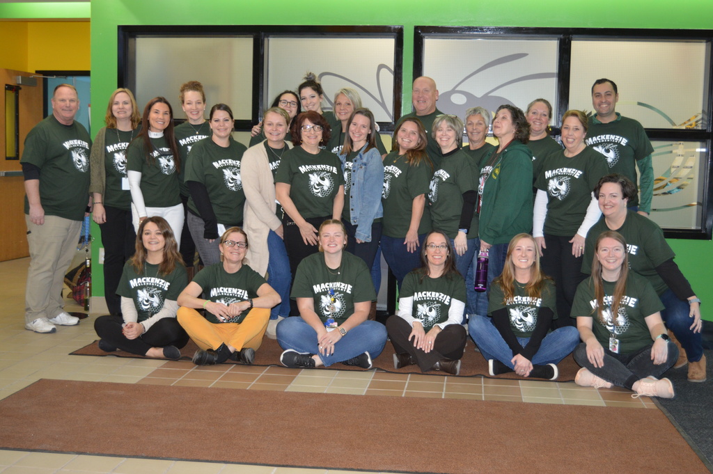 image of adults wearing green t-shirts with an image of a white yellow jacket and the works Mackenzie Elementary.
