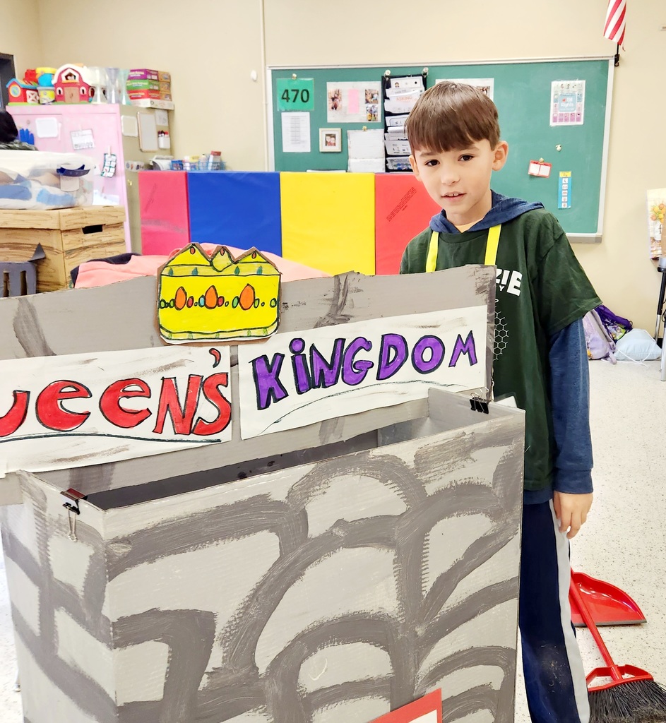 A male student stands behind a cardboard castle.