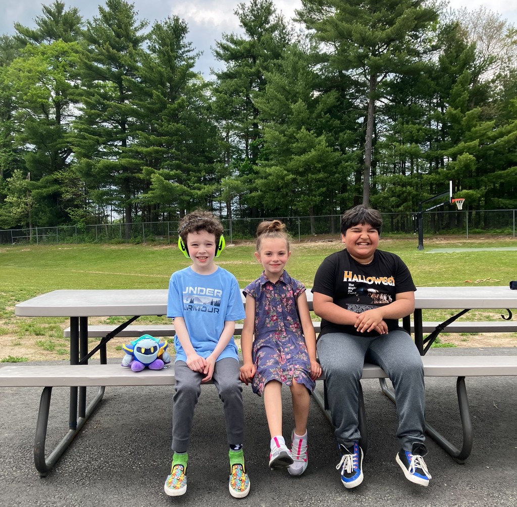 Image of three students sitting at a picnic table during outdoor club
