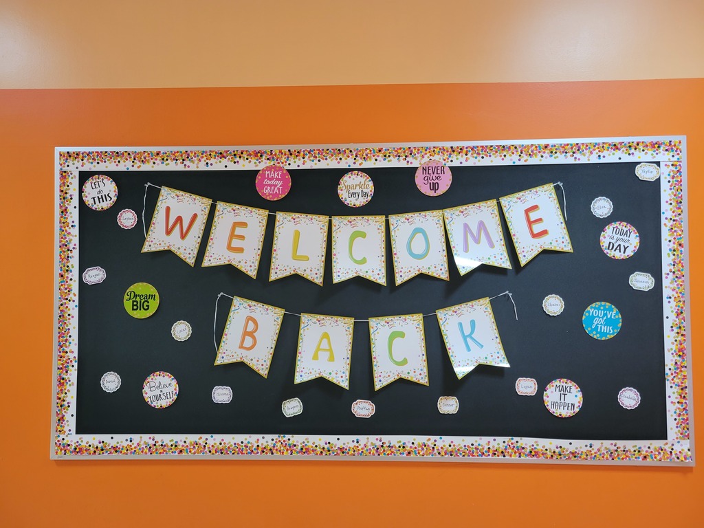 Orange wall with a black bulletin board with a banner that reads welcome back