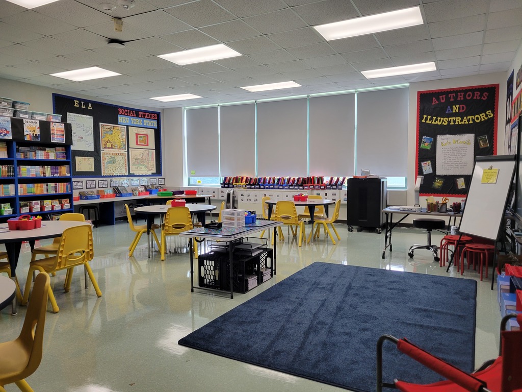 Image of a classroom set up with colorful chairs in the background and a blue carpet in the foreground