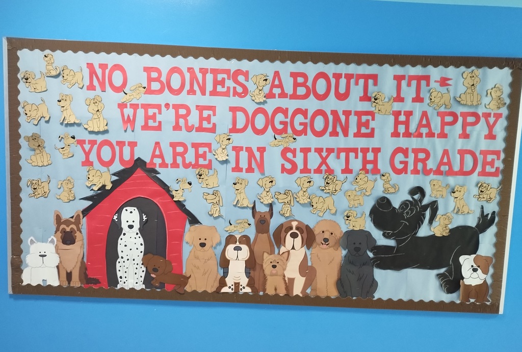 A blue wall with a bulletin board that reads No bones about it we're doggone happy you are in sixth grade there are a bunch of dogs and a doghouse