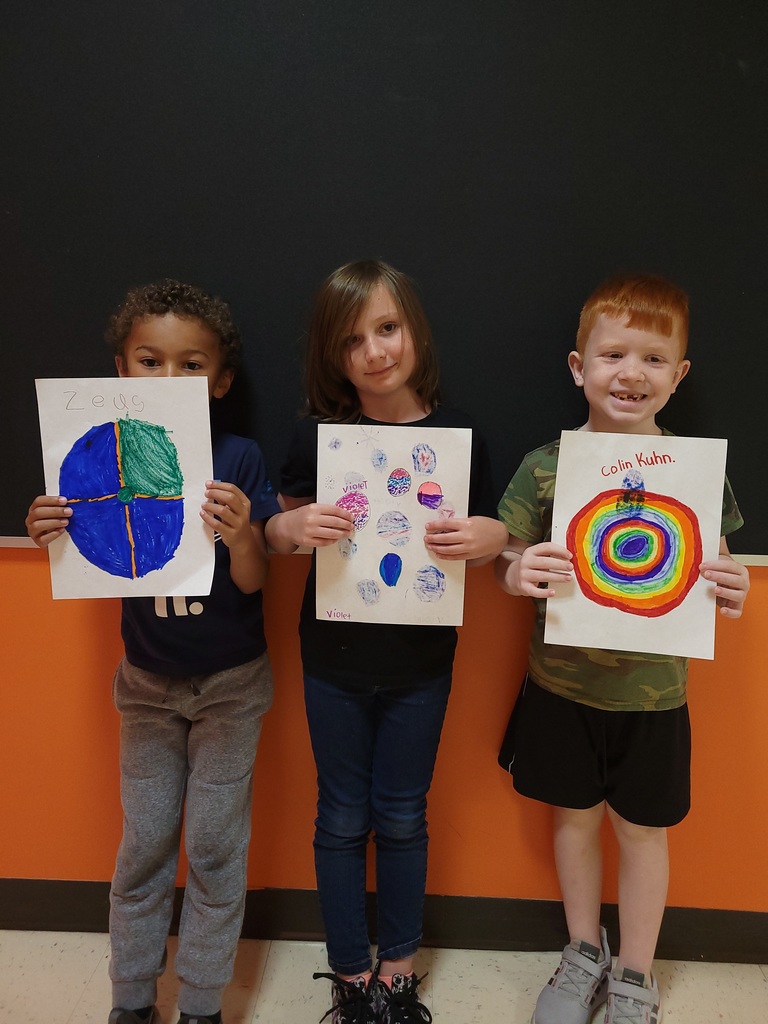 Students hold up art work they created for International Dot Day