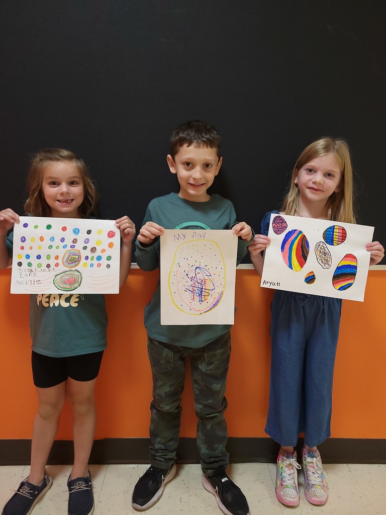 Students hold up art work they created for International Dot Day
