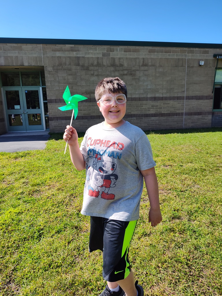 a student smiles while holding a green pinwheel